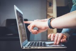 An account manager reviews customer data with a coworker on a laptop